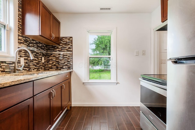 kitchen featuring appliances with stainless steel finishes, a sink, plenty of natural light, and baseboards