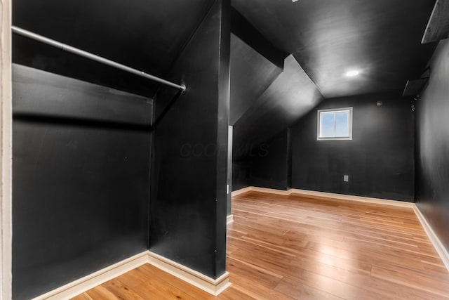 additional living space featuring baseboards, wood-type flooring, and vaulted ceiling