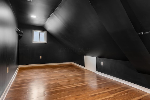 additional living space with vaulted ceiling, wood-type flooring, and baseboards