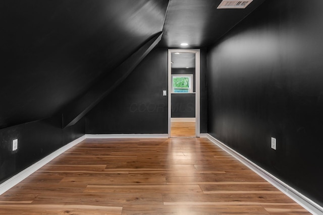 additional living space featuring wood finished floors, lofted ceiling, and baseboards