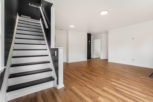 staircase with wood finished floors, baseboards, and recessed lighting