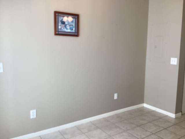 spare room with baseboards and light tile patterned flooring