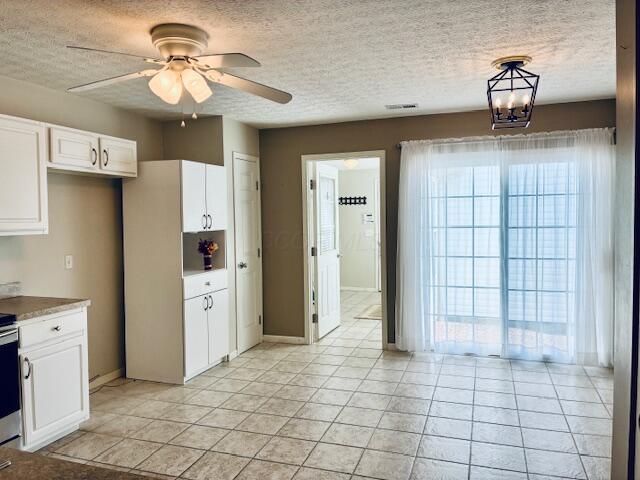 kitchen featuring a textured ceiling, white cabinetry, light tile patterned floors, a ceiling fan, and baseboards
