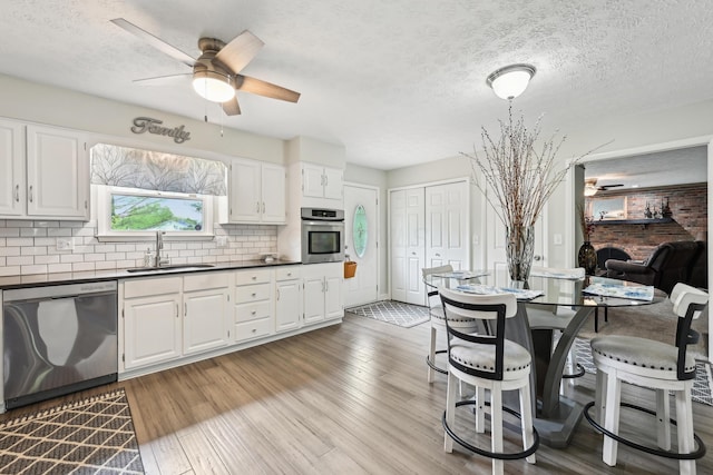 499 Wickham Way, Columbus, OH 43230 - kitchen with stainless steel appliances, a ceiling fan, a sink, dark countertops, and a textured ceiling