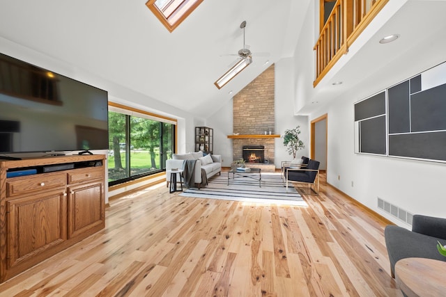 5657 Freeman Rd, Westerville, OH 43082 - living area featuring a skylight, high vaulted ceiling, a stone fireplace, light wood-style flooring, and ceiling fan