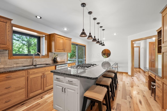 5657 Freeman Rd, Westerville, OH 43082 - kitchen featuring a sink, stainless steel gas stovetop, a kitchen breakfast bar, backsplash, and light wood-type flooring