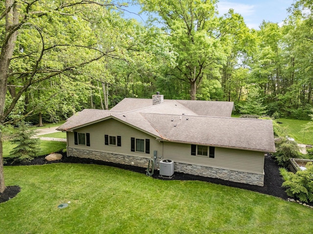 429 N Old State Rd, Delaware, OH 43015 - back of house featuring stone siding, cooling unit, a yard, a chimney, and roof with shingles
