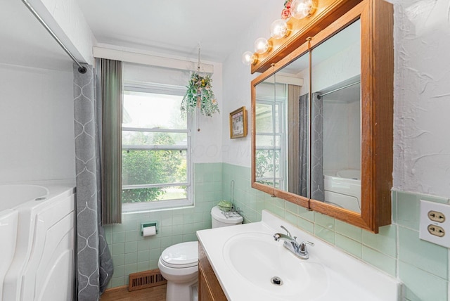 2747 Castlewood Rd, Columbus, OH 43209 - full bathroom with tile walls, toilet, a bath, vanity, and a shower