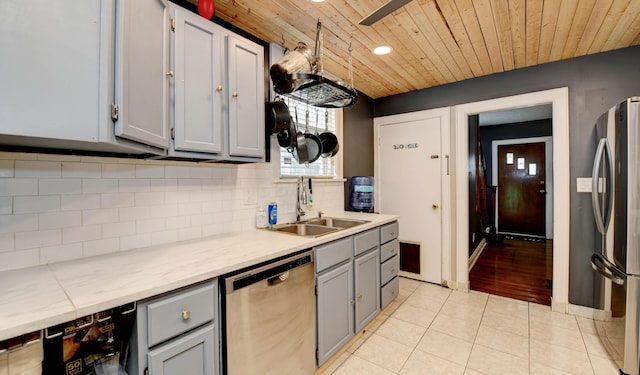 kitchen with stainless steel appliances, a sink, gray cabinets, wooden ceiling, and light tile patterned floors