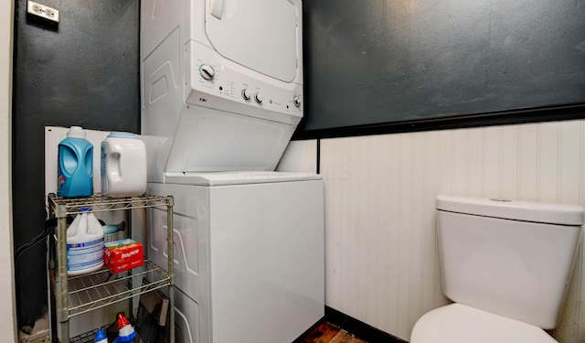 half bath featuring stacked washer and clothes dryer, toilet, and wood finished floors