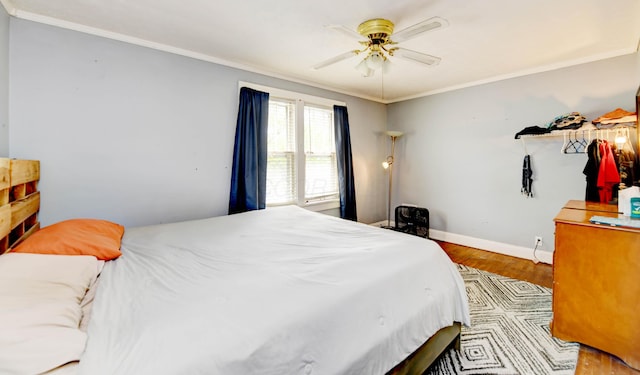 bedroom with wood finished floors, ornamental molding, baseboards, and ceiling fan