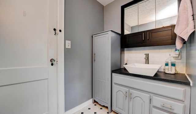 bathroom with tasteful backsplash, vanity, and baseboards