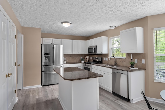 6289 Corley Dr, Dublin, OH 43016 - kitchen with stainless steel appliances, a sink, light wood finished floors, tasteful backsplash, and a textured ceiling
