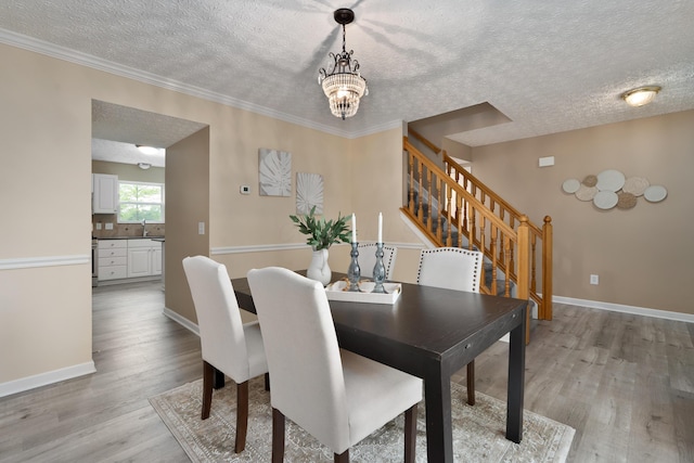 6289 Corley Dr, Dublin, OH 43016 - dining room with a textured ceiling, light wood-style flooring, a chandelier, stairs, and baseboards