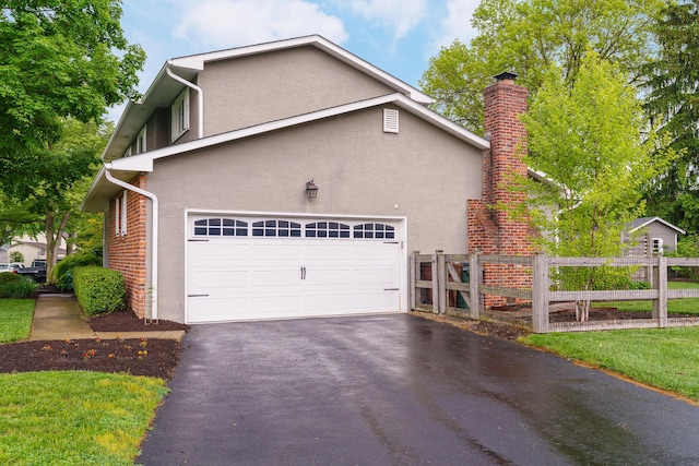 1671 Dollivor Dr, Columbus, OH 43235 - view of property exterior featuring stucco siding, fence, driveway, an attached garage, and a chimney