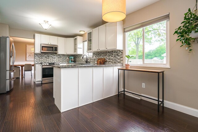 1671 Dollivor Dr, Columbus, OH 43235 - kitchen featuring appliances with stainless steel finishes, a peninsula, backsplash, and glass insert cabinets