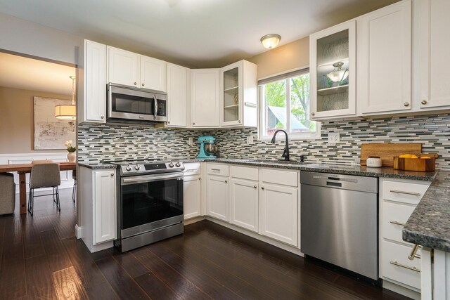 1671 Dollivor Dr, Columbus, OH 43235 - kitchen featuring appliances with stainless steel finishes, a sink, white cabinets, dark wood-type flooring, and dark stone counters