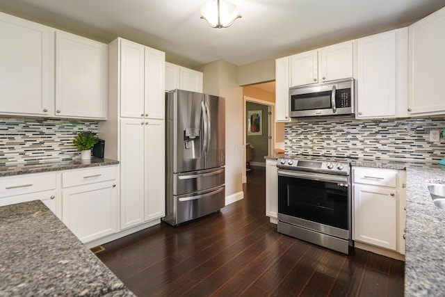 1671 Dollivor Dr, Columbus, OH 43235 - kitchen with stainless steel appliances, dark wood-style floors, dark stone countertops, tasteful backsplash, and white cabinetry