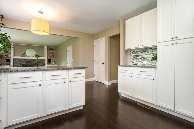 1671 Dollivor Dr, Columbus, OH 43235 - kitchen with decorative backsplash, dark wood finished floors, white cabinetry, dark stone countertops, and baseboards