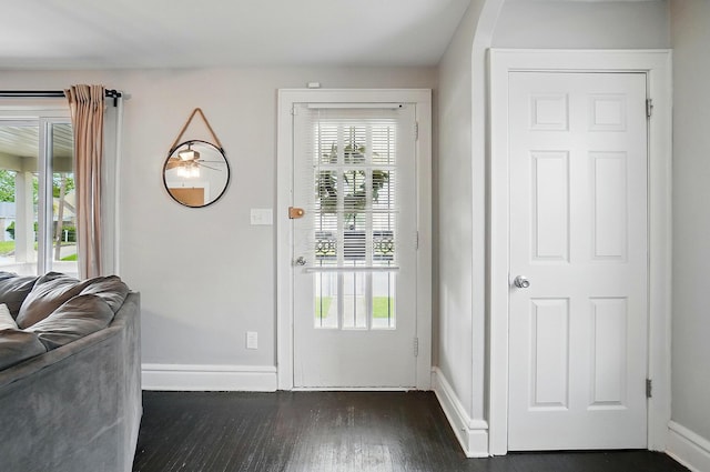doorway with baseboards, dark wood-style floors, and healthy amount of natural light