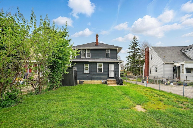 rear view of property featuring a chimney, a storage unit, entry steps, and an outbuilding