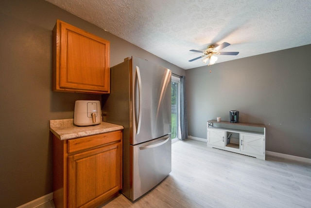 3233 Burdett Ct, Columbus, OH 43232 - kitchen featuring freestanding refrigerator, ceiling fan, a textured ceiling, light wood-type flooring, and brown cabinets