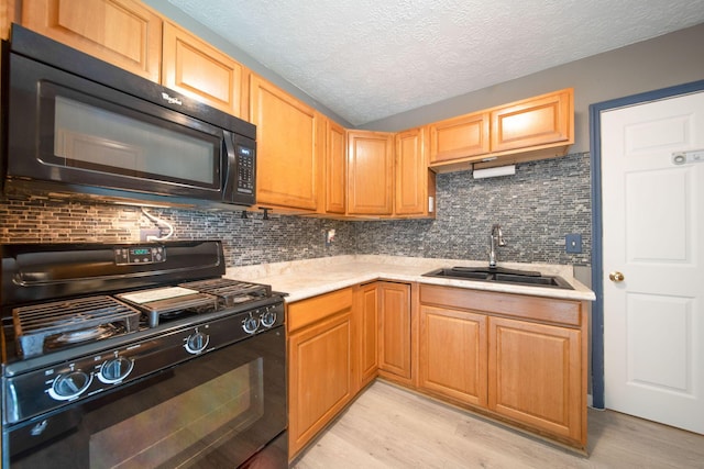 3233 Burdett Ct, Columbus, OH 43232 - kitchen with black appliances, a sink, light wood-type flooring, light countertops, and a textured ceiling