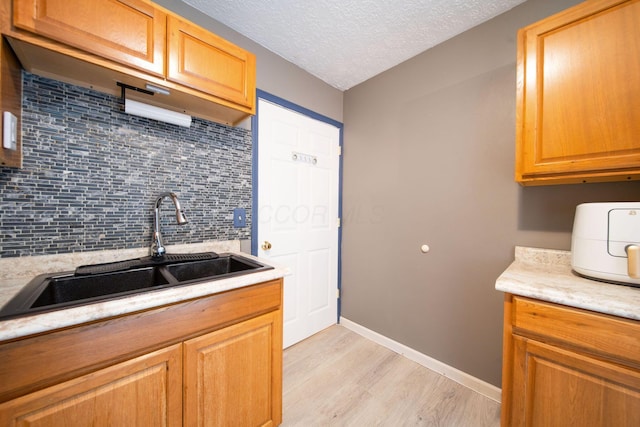 3233 Burdett Ct, Columbus, OH 43232 - kitchen featuring a sink, light countertops, light wood-style flooring, tasteful backsplash, and a textured ceiling