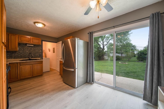 3233 Burdett Ct, Columbus, OH 43232 - kitchen with freestanding refrigerator, a sink, brown cabinetry, a textured ceiling, and light wood-type flooring