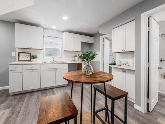 2767 Hiawatha St, Columbus, OH 43211 - kitchen featuring a sink, wood finished floors, decorative backsplash, white cabinetry, and light countertops