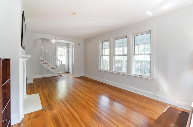 789 Chelsea Ave, Columbus, OH 43209 - unfurnished living room featuring arched walkways, baseboards, stairway, and light wood-style floors