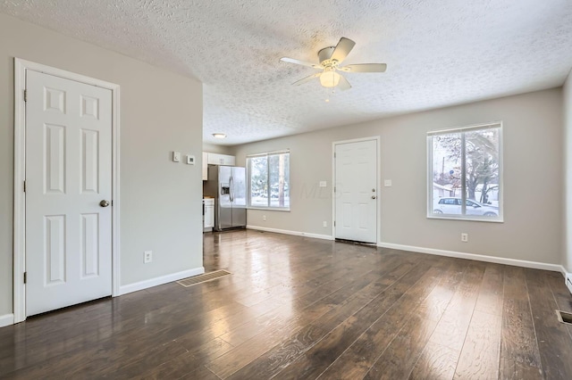 unfurnished living room featuring a textured ceiling, ceiling fan, dark wood-style flooring, and baseboards