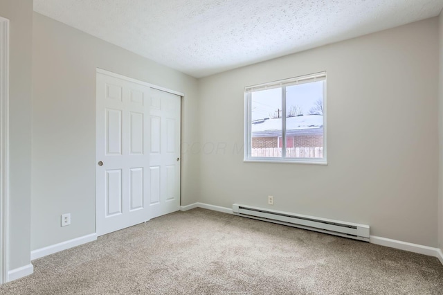 unfurnished bedroom featuring a baseboard heating unit, carpet, baseboards, a closet, and a textured ceiling