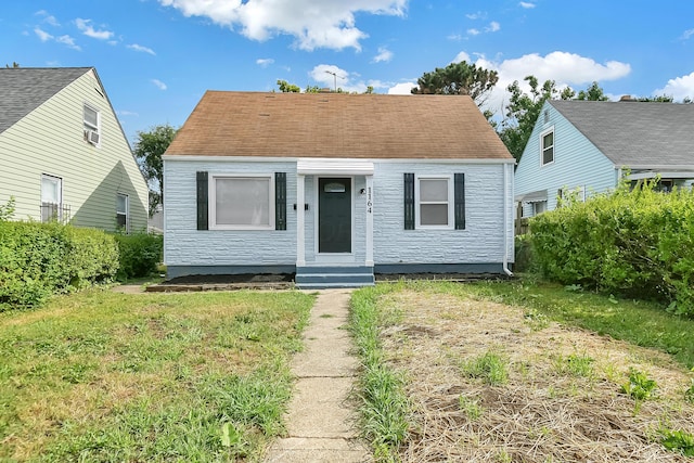 view of front of property with roof with shingles, a front lawn, and entry steps