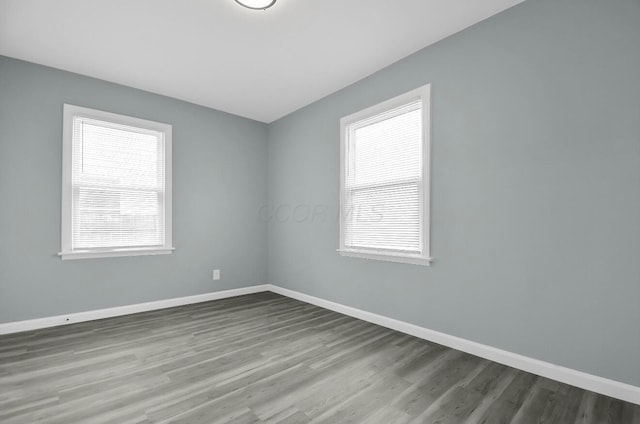 unfurnished room featuring healthy amount of natural light, baseboards, and wood finished floors