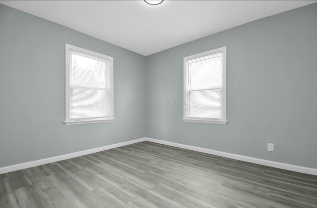 spare room with baseboards and wood finished floors