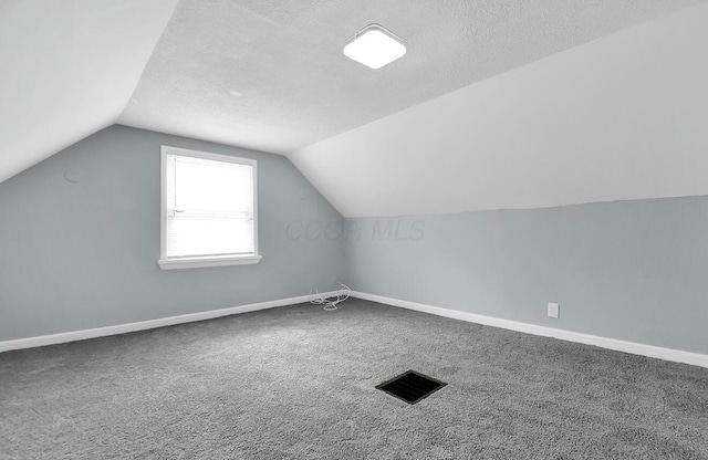 bonus room with lofted ceiling, carpet, baseboards, and a textured ceiling