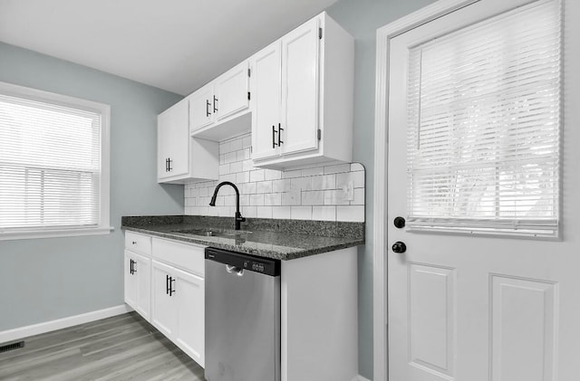kitchen with dishwasher, a sink, white cabinetry, decorative backsplash, and light wood-style flooring