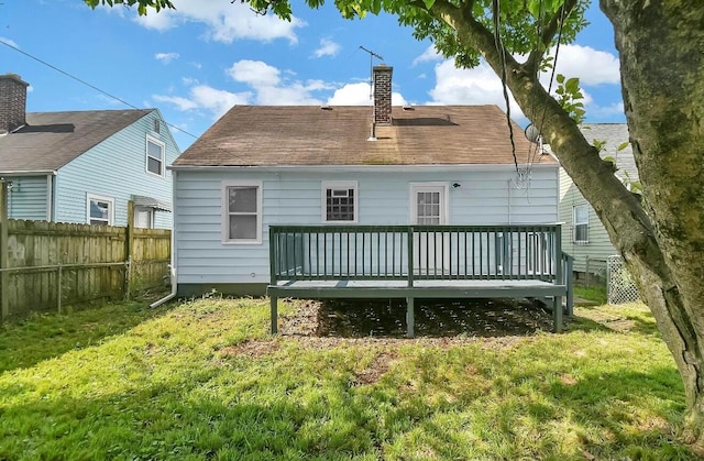 back of property with a deck, a chimney, and a shingled roof