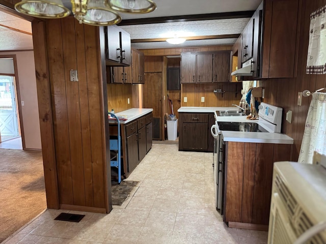kitchen featuring white electric range, under cabinet range hood, wood walls, light countertops, and a sink