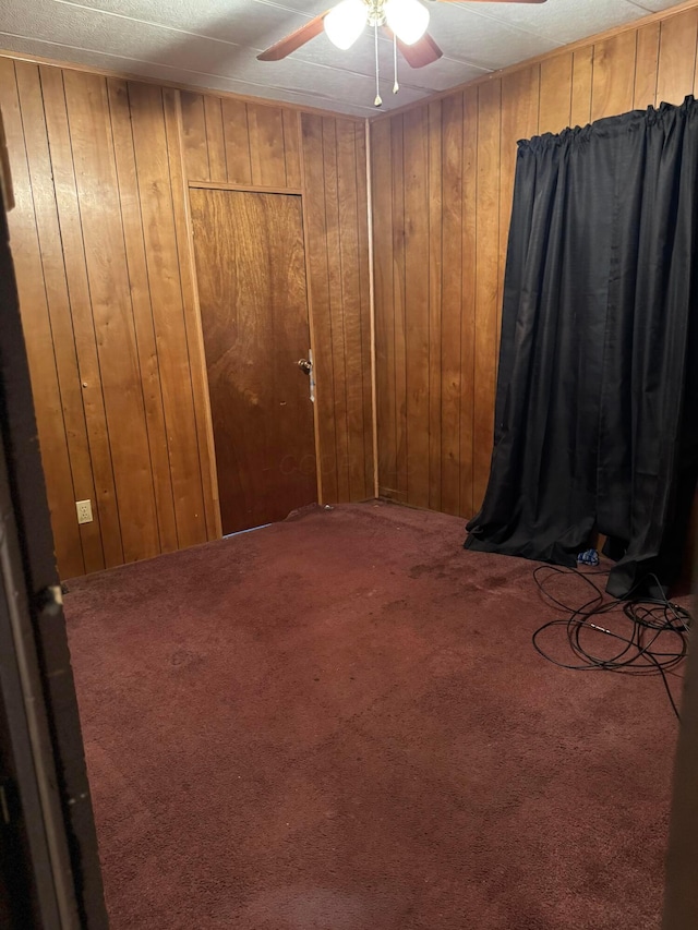 carpeted spare room with ceiling fan and wooden walls