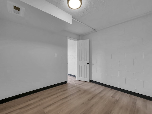 empty room with wood finished floors, baseboards, and a textured ceiling
