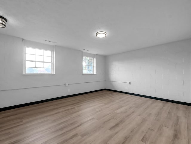 unfurnished room featuring wood finished floors, baseboards, and concrete block wall