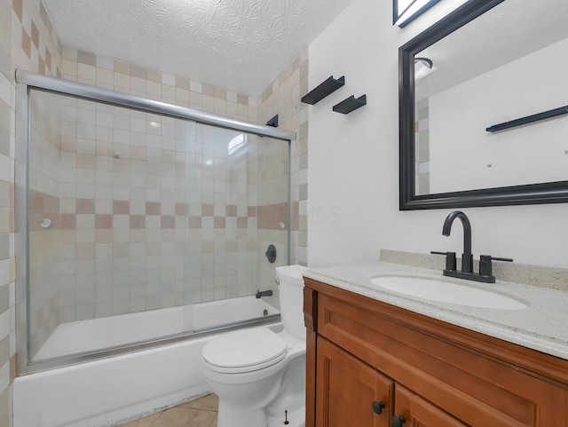 full bath featuring toilet, tile patterned floors, shower / bath combination with glass door, vanity, and a textured ceiling