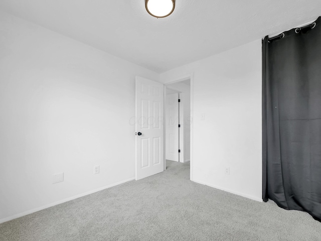 unfurnished room with carpet flooring and baseboards