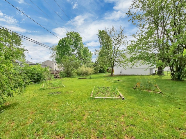 view of grassy yard featuring a garden