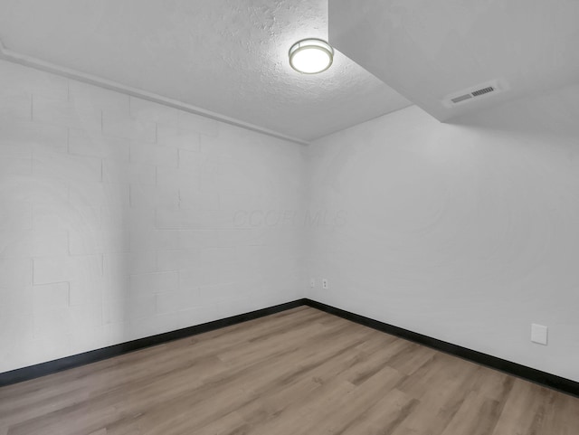 empty room with wood finished floors, baseboards, and a textured ceiling