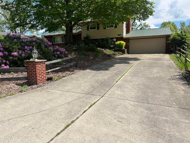 view of front of property featuring fence, a garage, concrete driveway, and metal roof