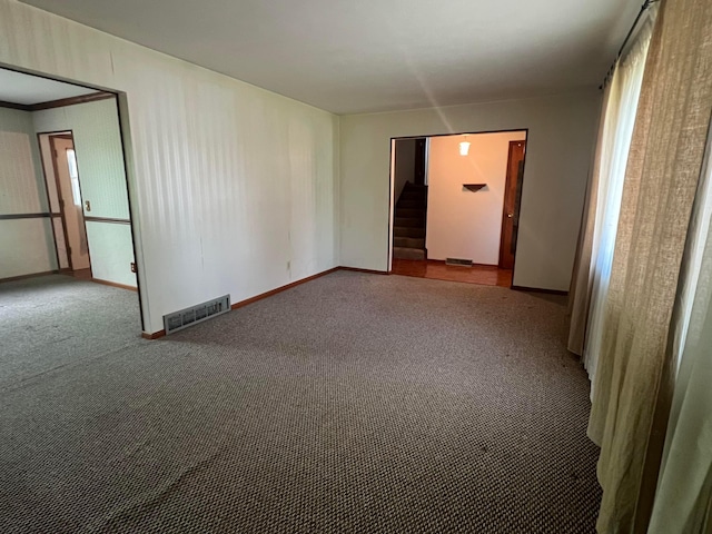 spare room featuring stairs, carpet flooring, and baseboards