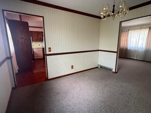 empty room featuring a chandelier, carpet floors, wallpapered walls, baseboards, and ornamental molding